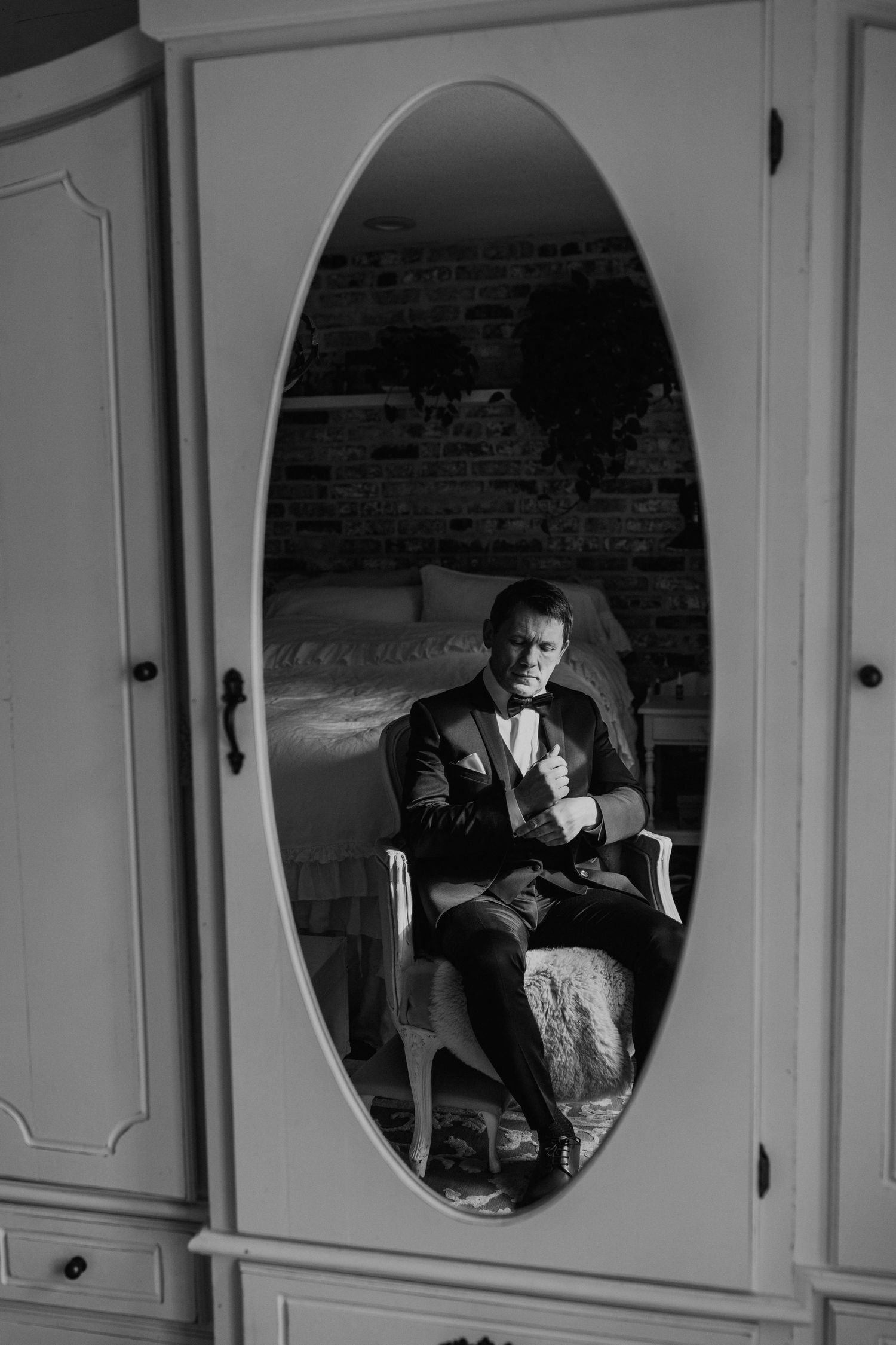 A reflection in an oval mirror shows a formal portrait in a vintage-styled room.