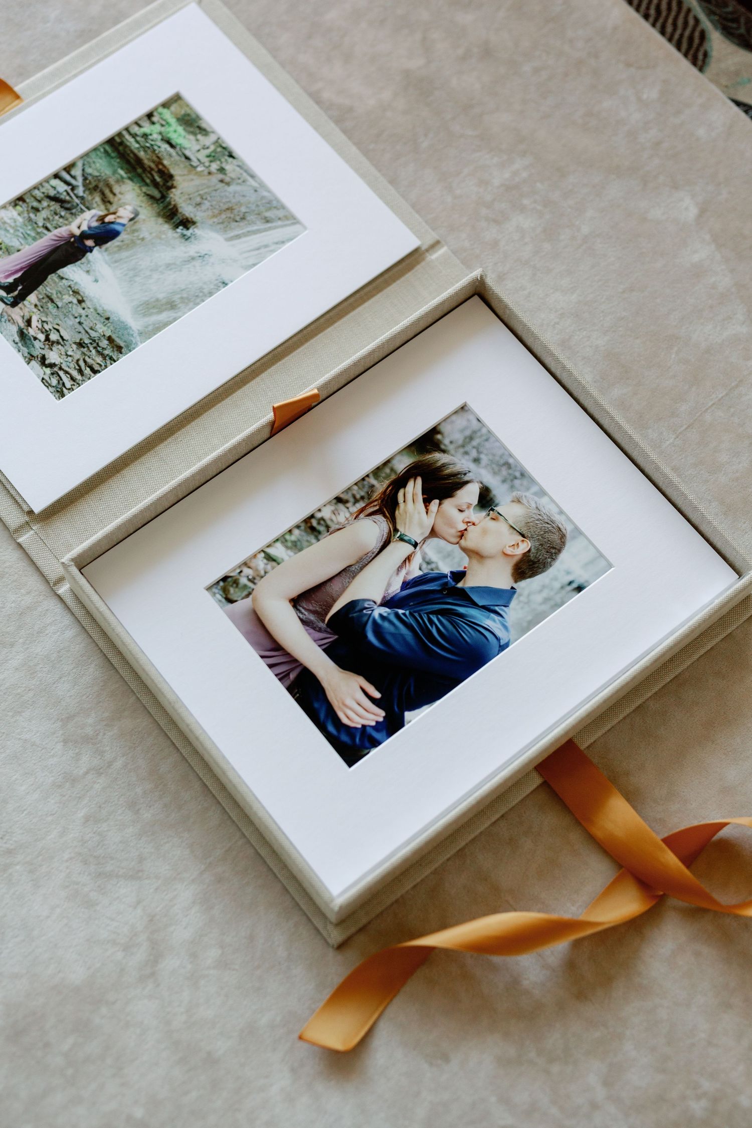 A photo album is open to a photo of a young couple sharing a kiss in their photoshoot.