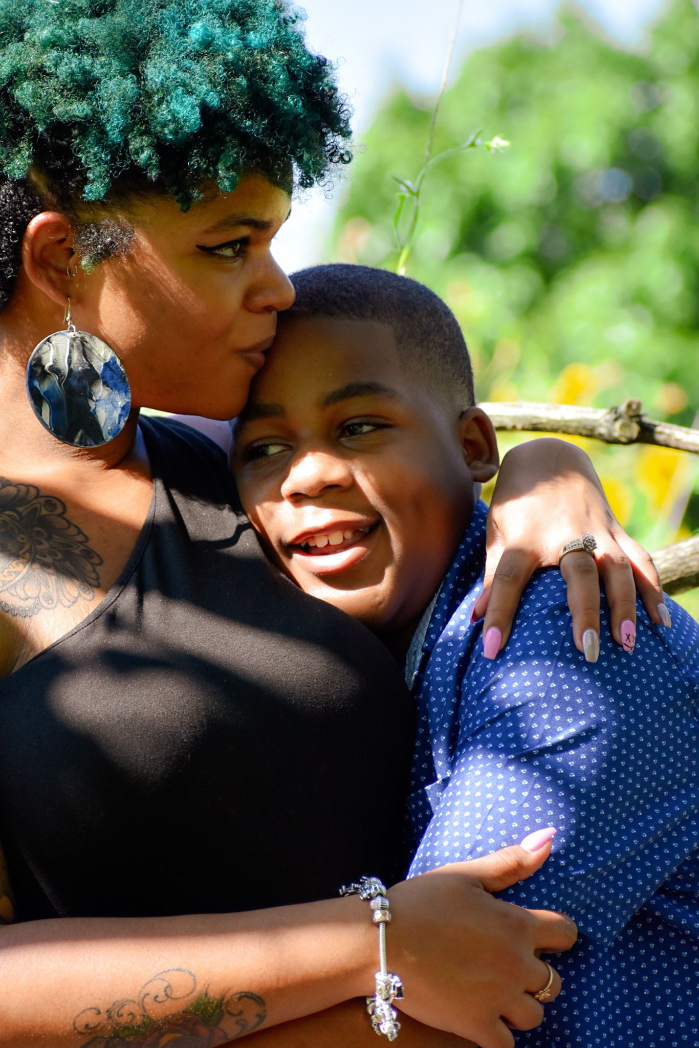 A warm embrace captured outdoors on a sunny day with natural greenery in the background.