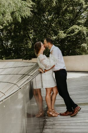 A couple shares an intimate moment on a wooden deck outdoors.