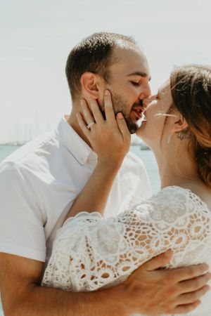 A romantic moment captured between a couple in white attire against a bright background.