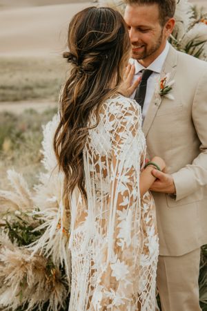 Intimate desert wedding portrait featuring lace dress details and natural desert lighting.