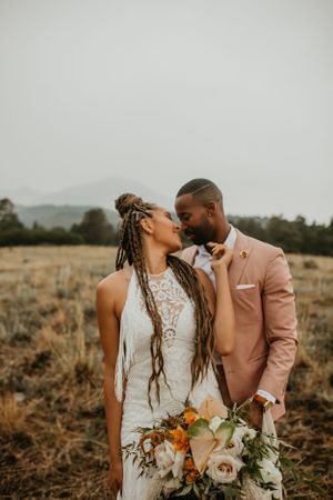 A couple in wedding attire sharing a joyful moment in a rustic outdoor setting.