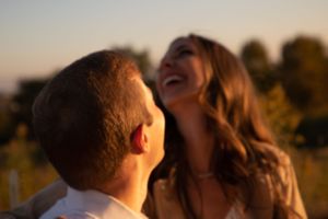 Candid laughter shared between couple during outdoor sunset photoshoot.
