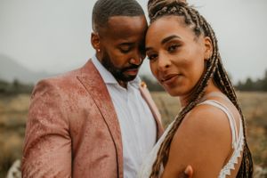 Romantic outdoor portrait of a couple in formal attire with mountains in the background.