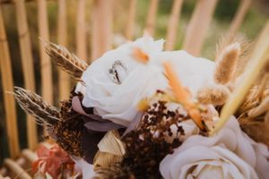 Rustic floral arrangement with white roses and dried elements.