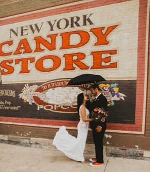 Wedding couple posing playfully in front of vintage candy store signage.
