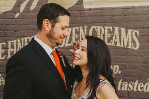Couple posing against urban wall with vintage advertising signage.
