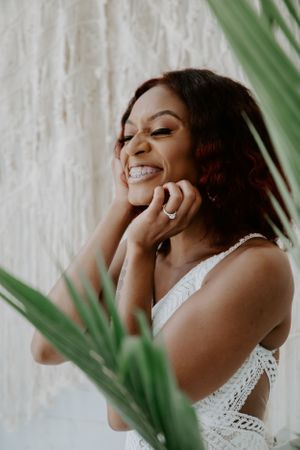 Candid moments of joy and laughter in a bright white bridal setting with tropical greenery.