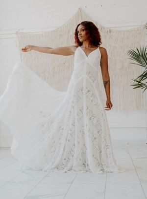 A flowing white lace wedding dress twirls gracefully against a light backdrop with palm leaves.