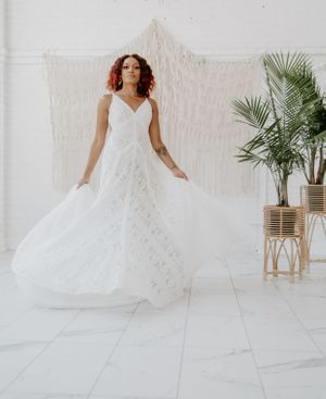 A flowing white wedding gown creates movement against a minimalist white studio backdrop.