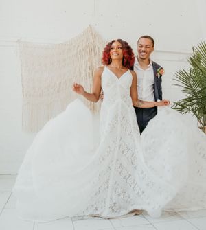 A couple dances and spins in wedding attire against a bright white backdrop.