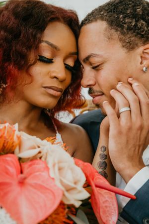 Romantic wedding portrait with coral flowers and intimate expressions.