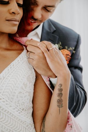 Close-up detail of floral tattoo and intimate moment between couple.