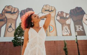 Wedding couple poses in front of a wall featuring raised fist artwork.