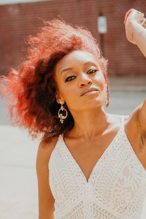 Bride with vibrant red hair poses in front of an artistic wall mural.