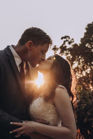 A romantic sunset kiss between newlyweds with golden light streaming through.