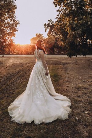 Beautiful wedding dress with lace details and flowing train photographed at sunset.