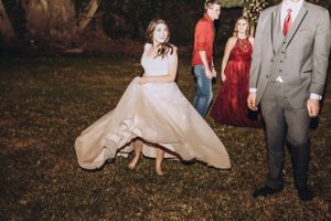 Wedding party in burgundy dresses and gray suits dancing outdoors.