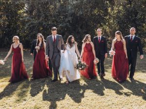Wedding party in burgundy dresses and formal attire posing outdoors.
