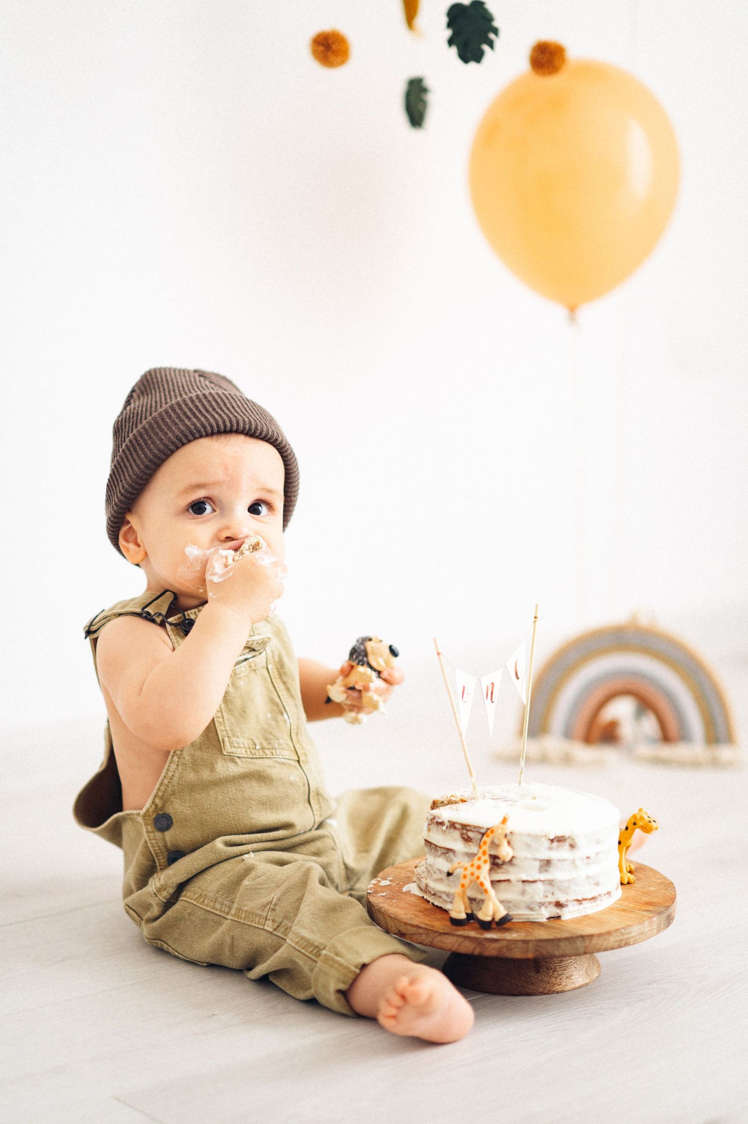 Birthday celebration setup with beige and orange decor featuring a white layered cake.