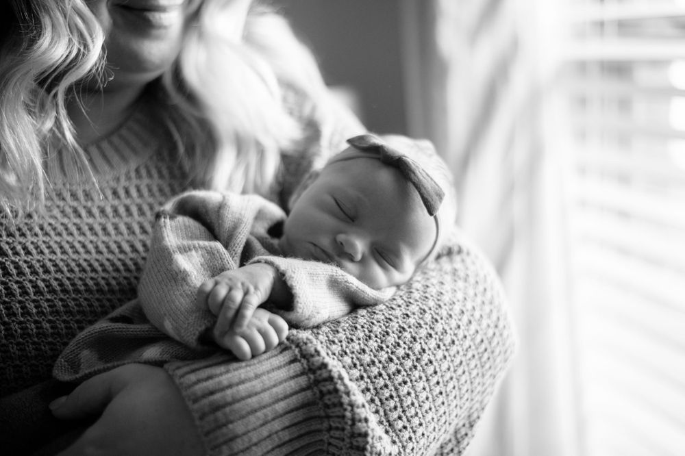 A black and white portrait of a sleeping newborn in soft window light.