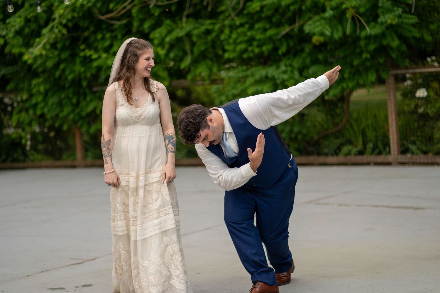 Fun candid moment of couple dancing at outdoor wedding reception.