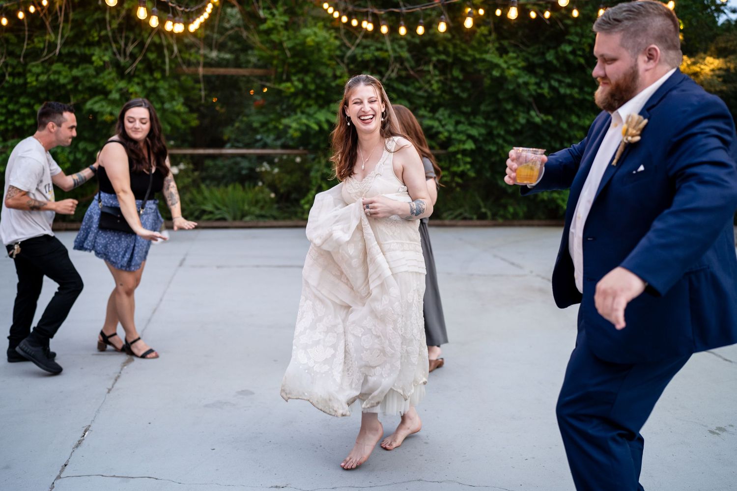 Wedding guests dancing and having fun on outdoor patio with string lights overhead.