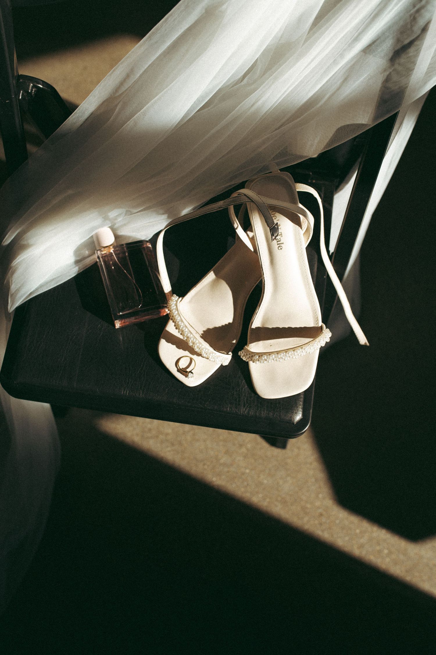 Wedding shoes and flowing white dress veil captured in dramatic lighting and shadows.