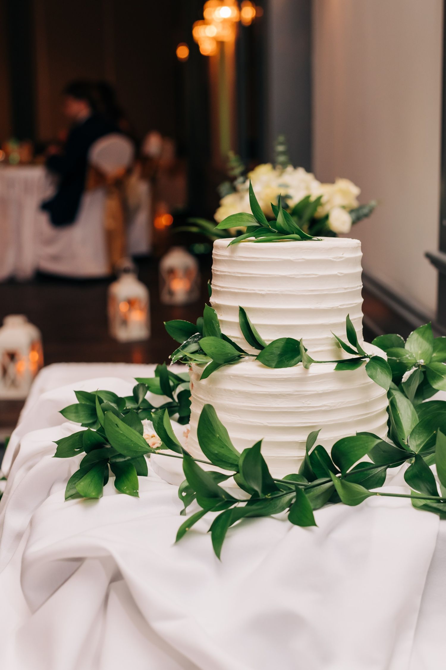 white wedding cake with greenery at wedding reception