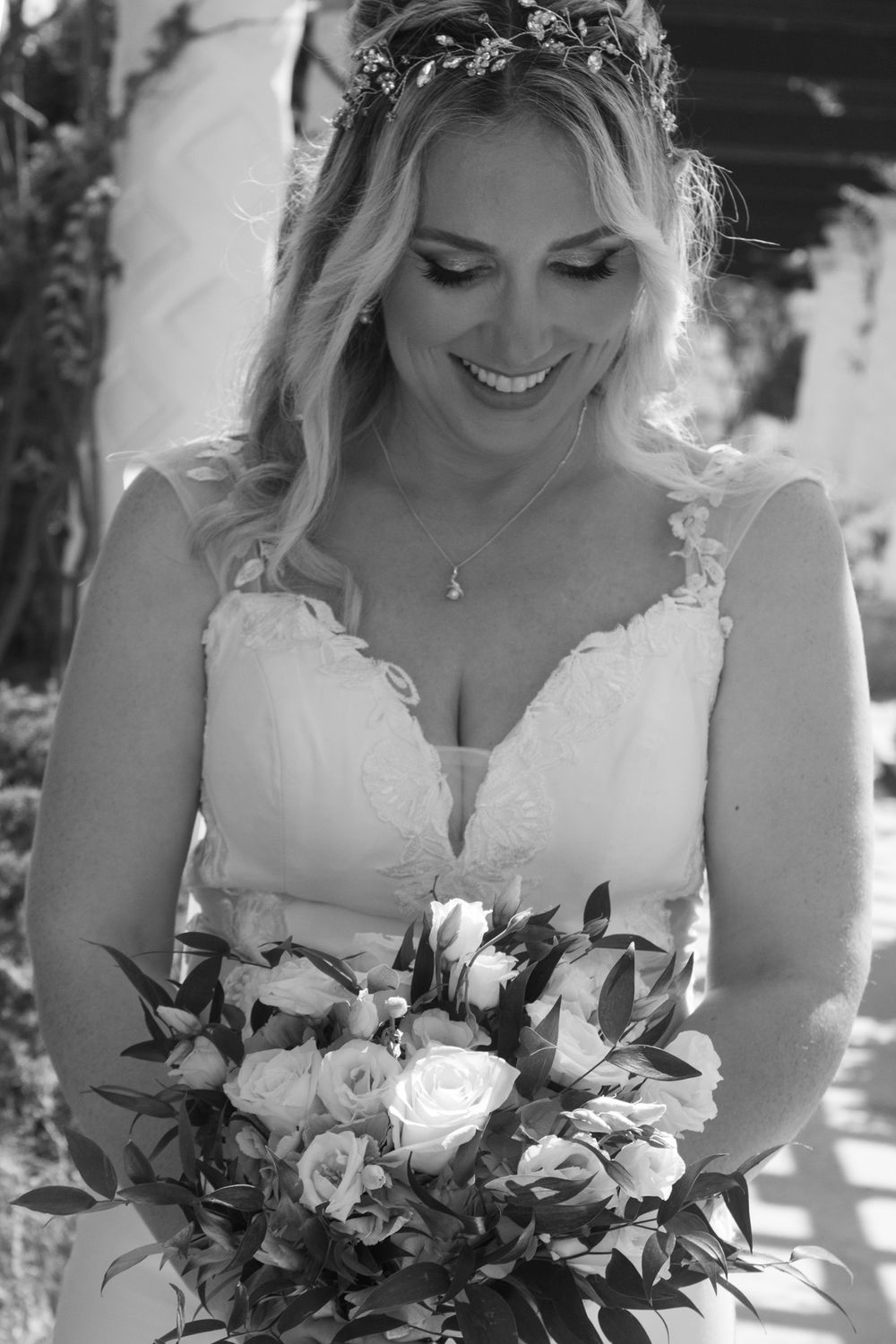 Elegant bridal portrait featuring a floral crown and white bouquet in black and white.
