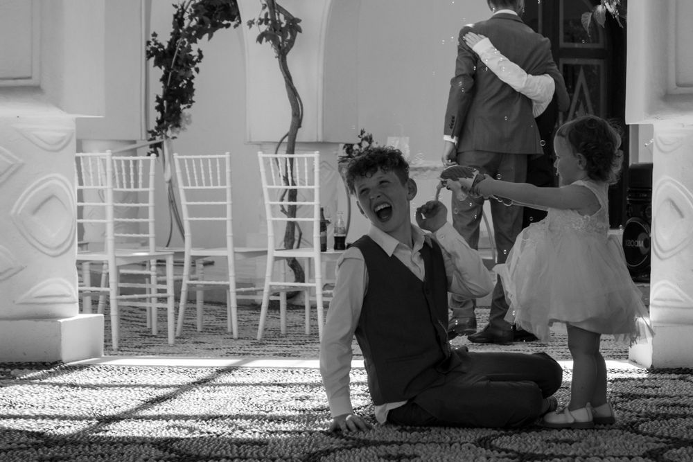 Black and white candid moment captured between guests during wedding reception.