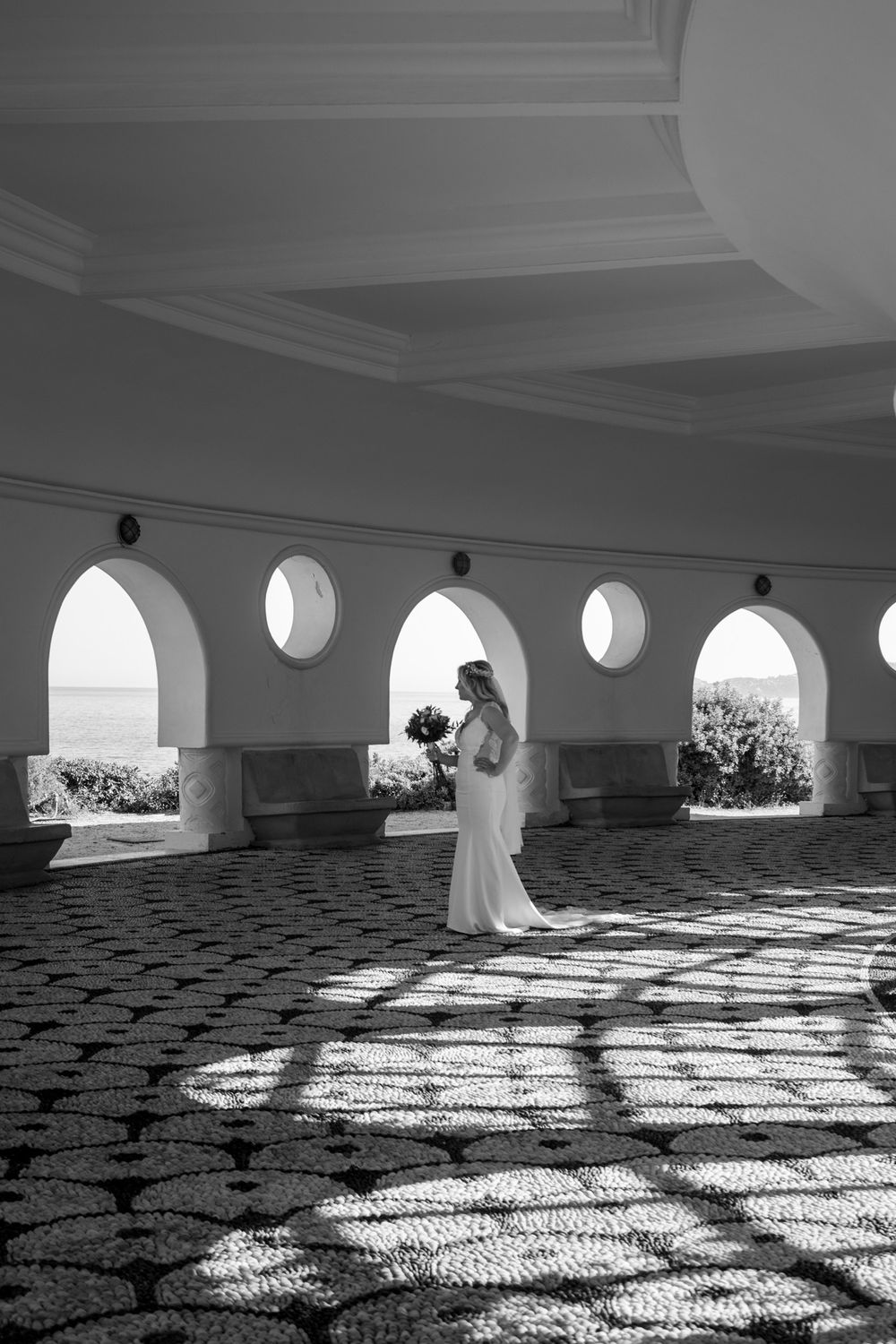 Black and white architectural photo showing patterned shadows through arched windows.