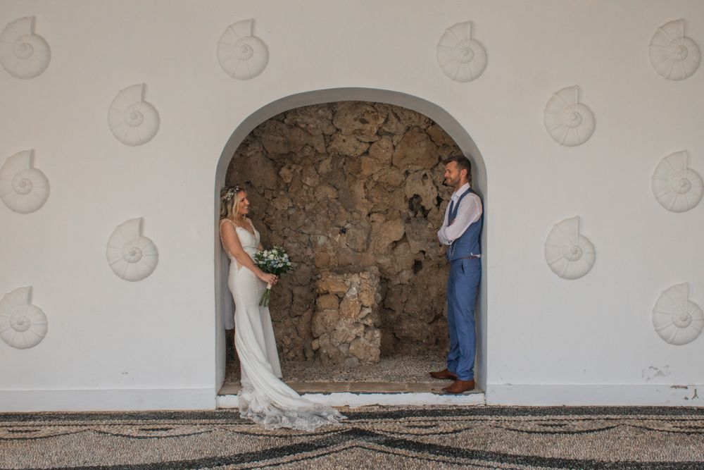 Couple posing in stone archway during intimate wedding photoshoot.
