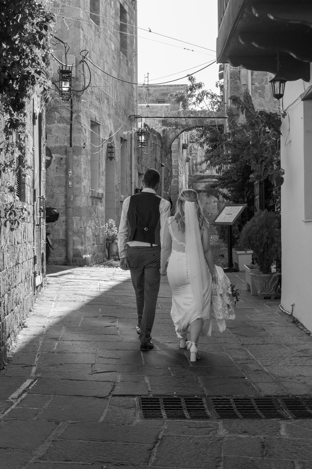 Black and white photo of couple walking through charming Italian alleyway.