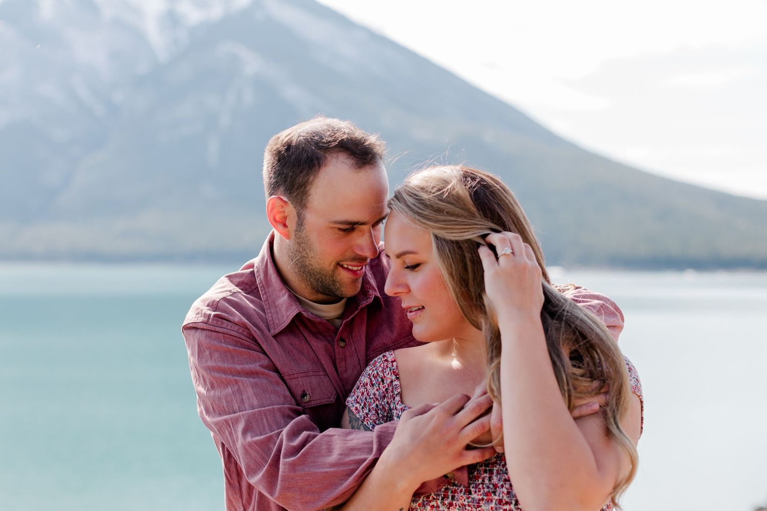 Intimate moment captured by turquoise mountain lake under cloudy skies.