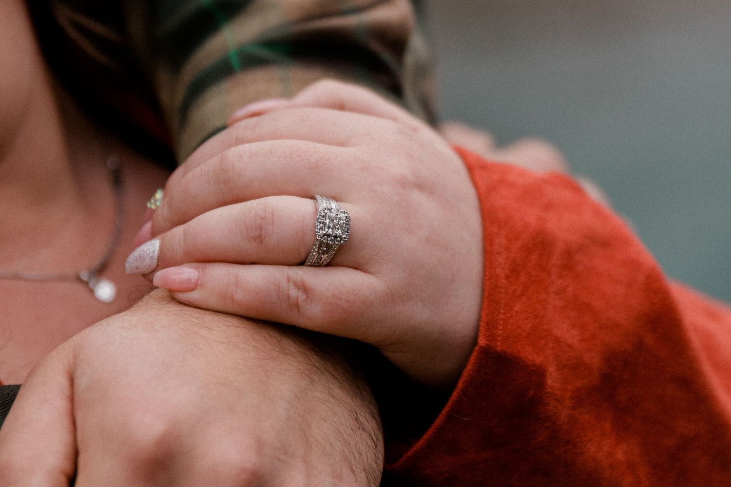 Close-up shot of hands wearing an ornate silver ring against a red fabric background.