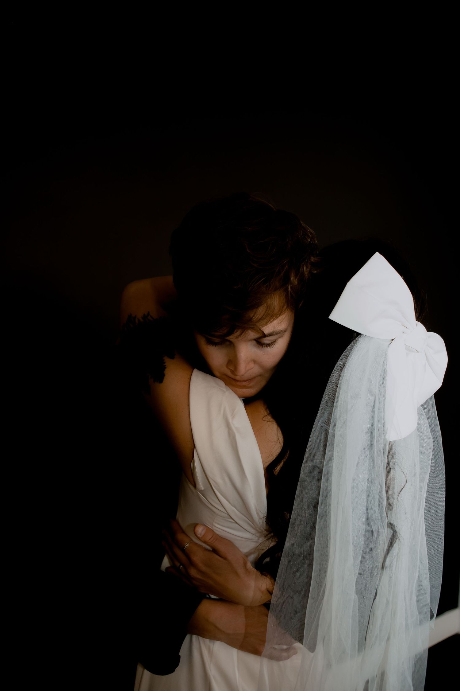Intimate dark and moody portrait featuring white wedding veil and dress details.