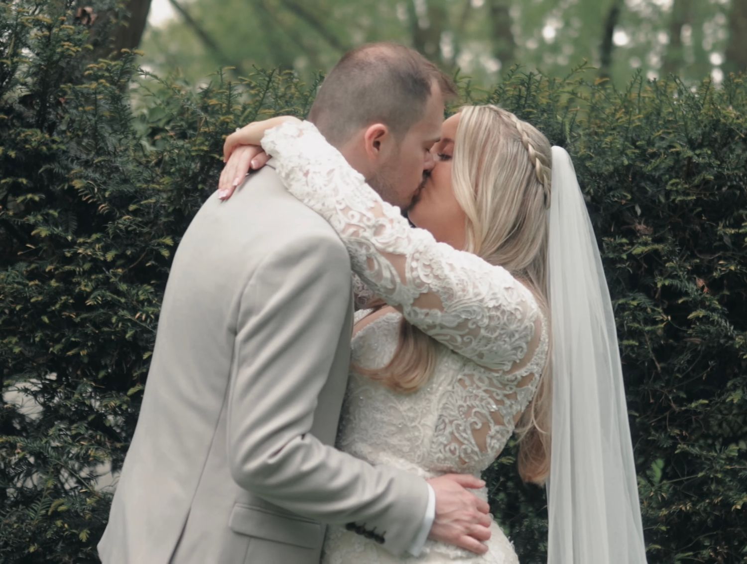 A romantic wedding kiss captured in a lush garden setting.