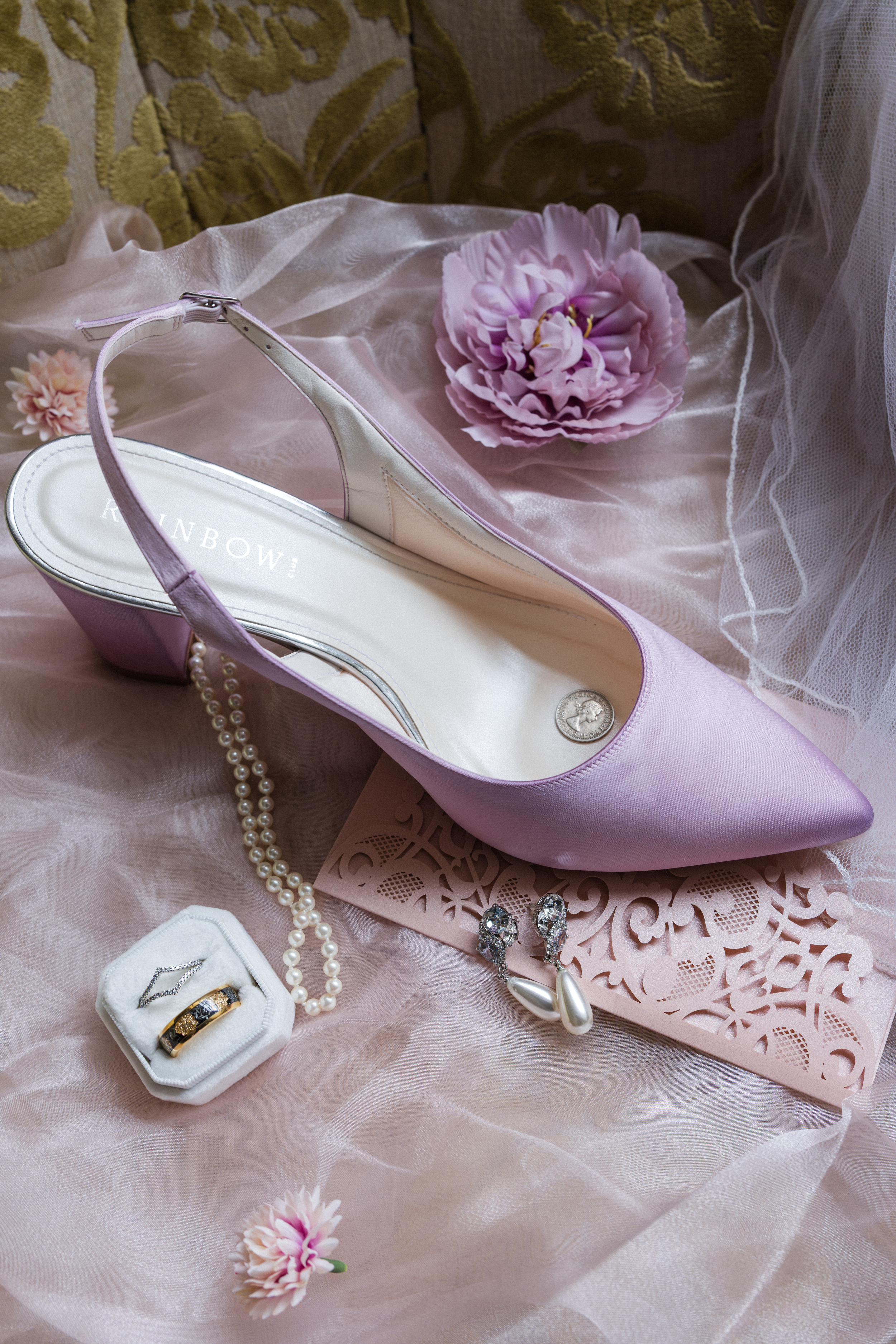 Delicate pink slingback shoes with pearl accessories and floral details on soft fabric.