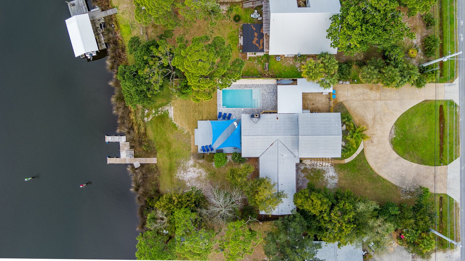 Aerial view of waterfront property with pool and boat dock on residential canal.