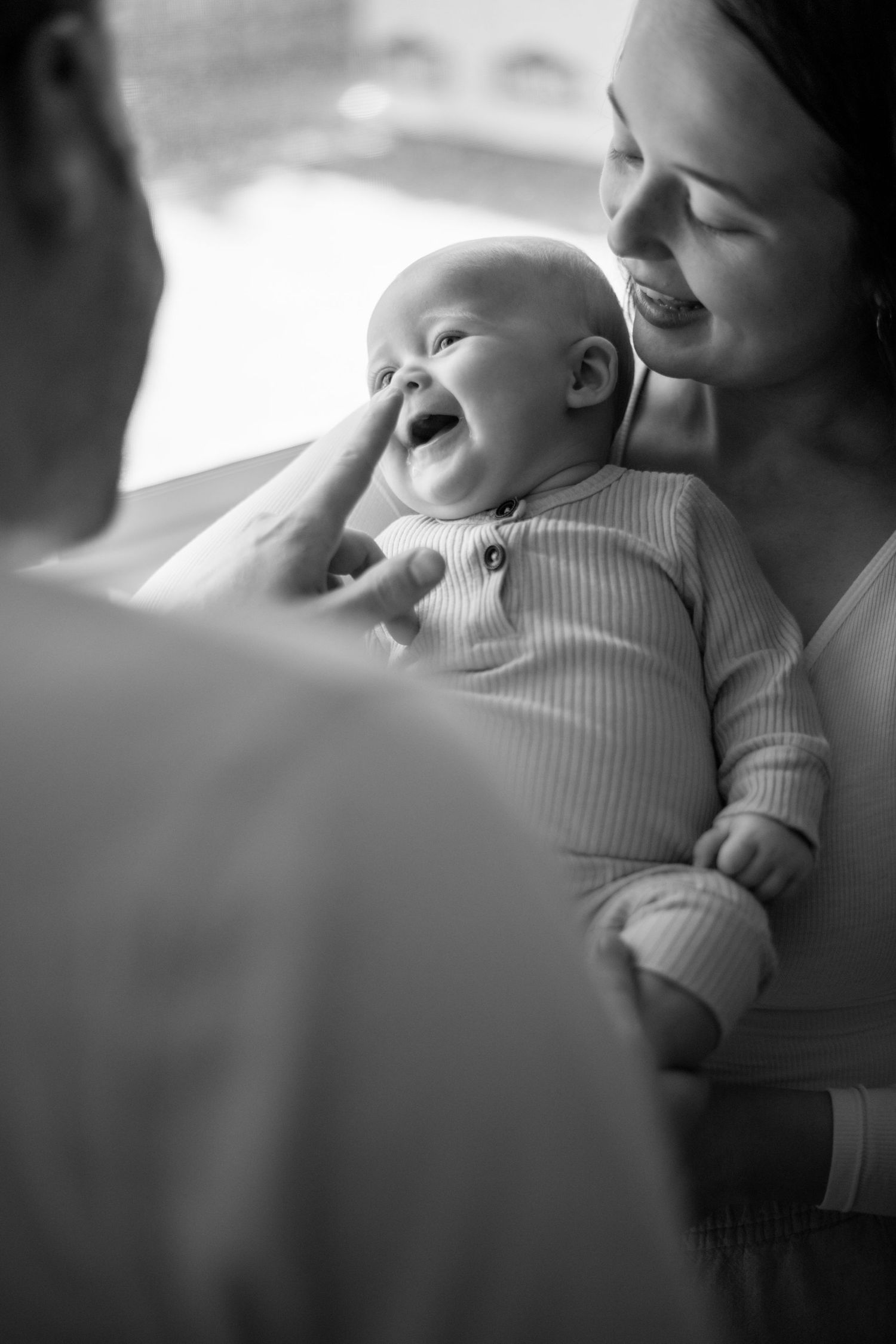 A laughing baby in striped clothing brings joy during a tender family moment.