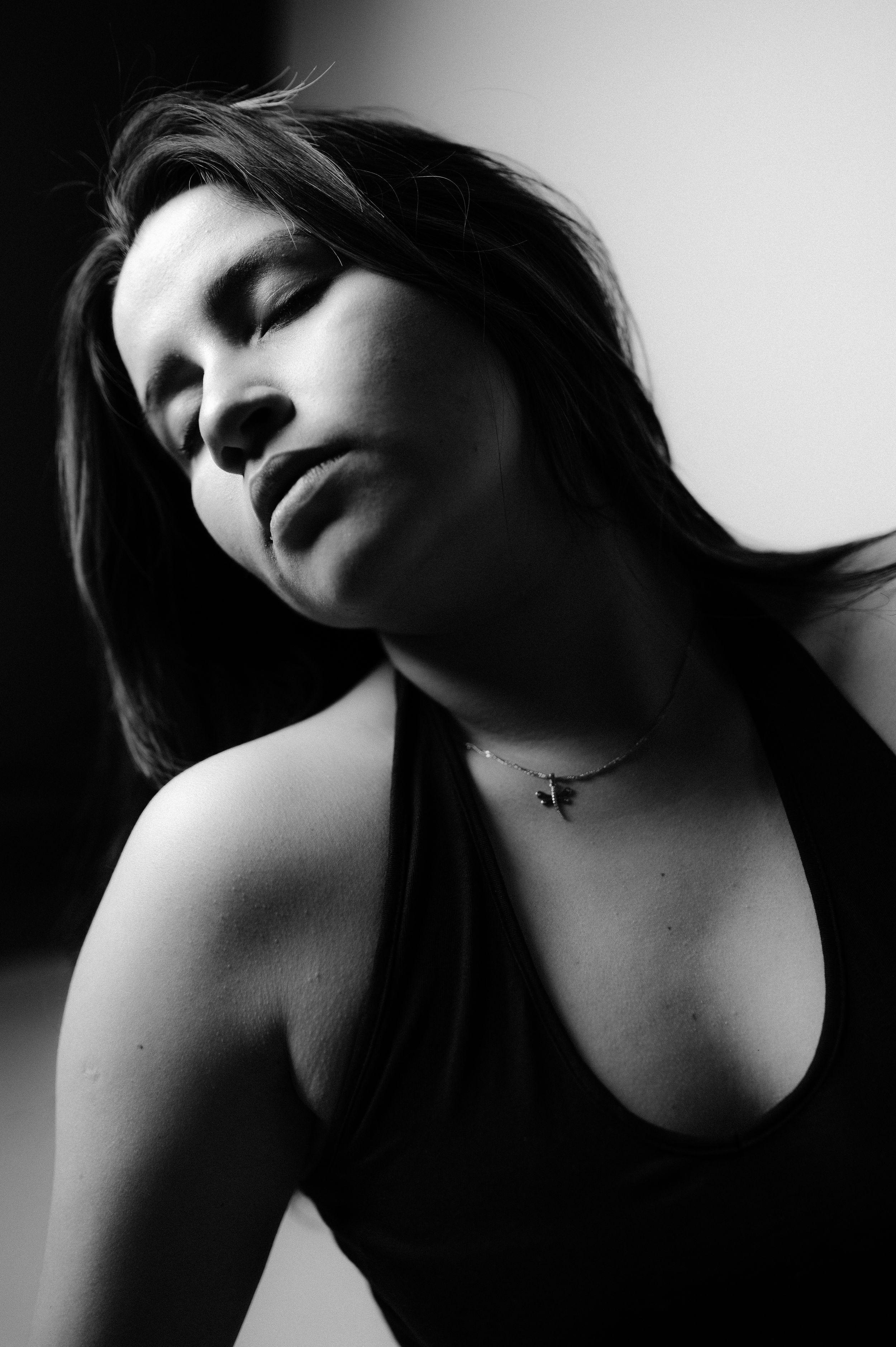 Dramatic black and white portrait with strong contrast showing necklace detail.