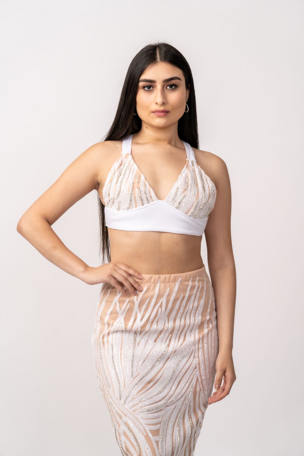 Fashion model poses in white and beige patterned two-piece outfit against light background.