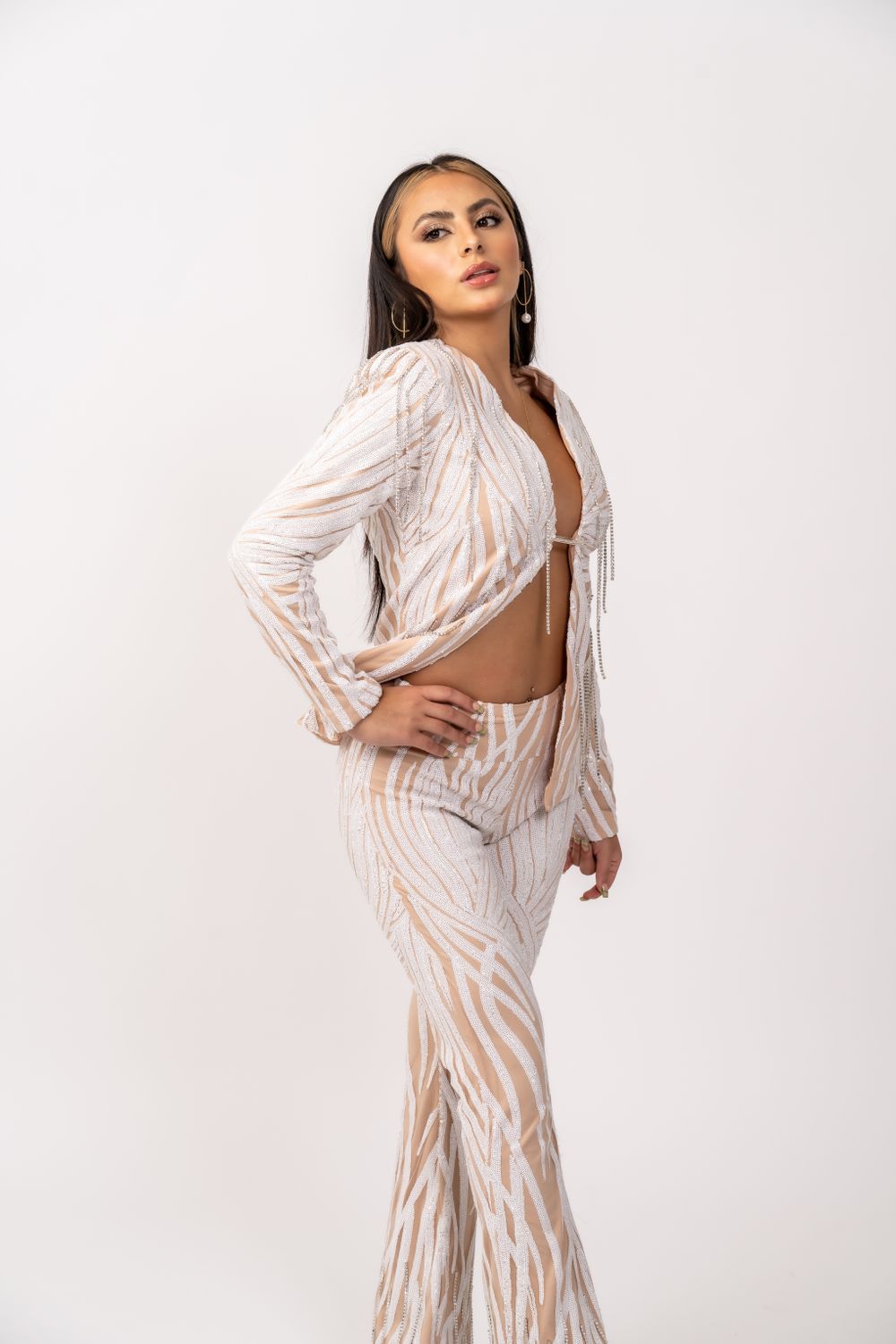 Model wearing white and beige patterned two-piece outfit with long sleeves.
