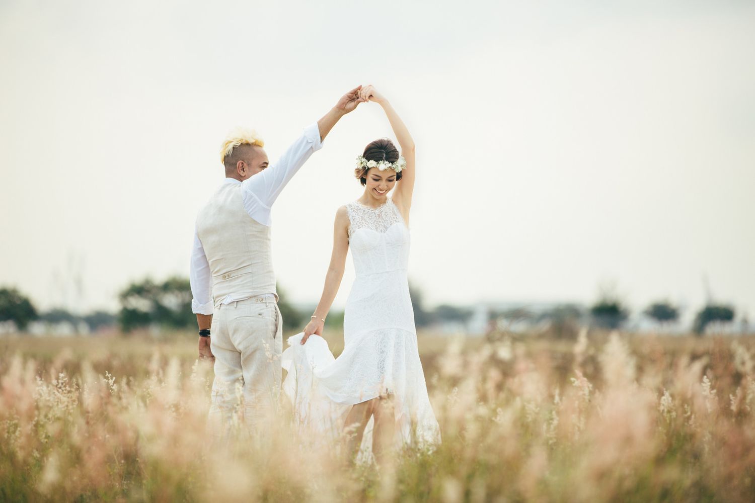 Couple dancing together in golden field during sunset photo shoot.