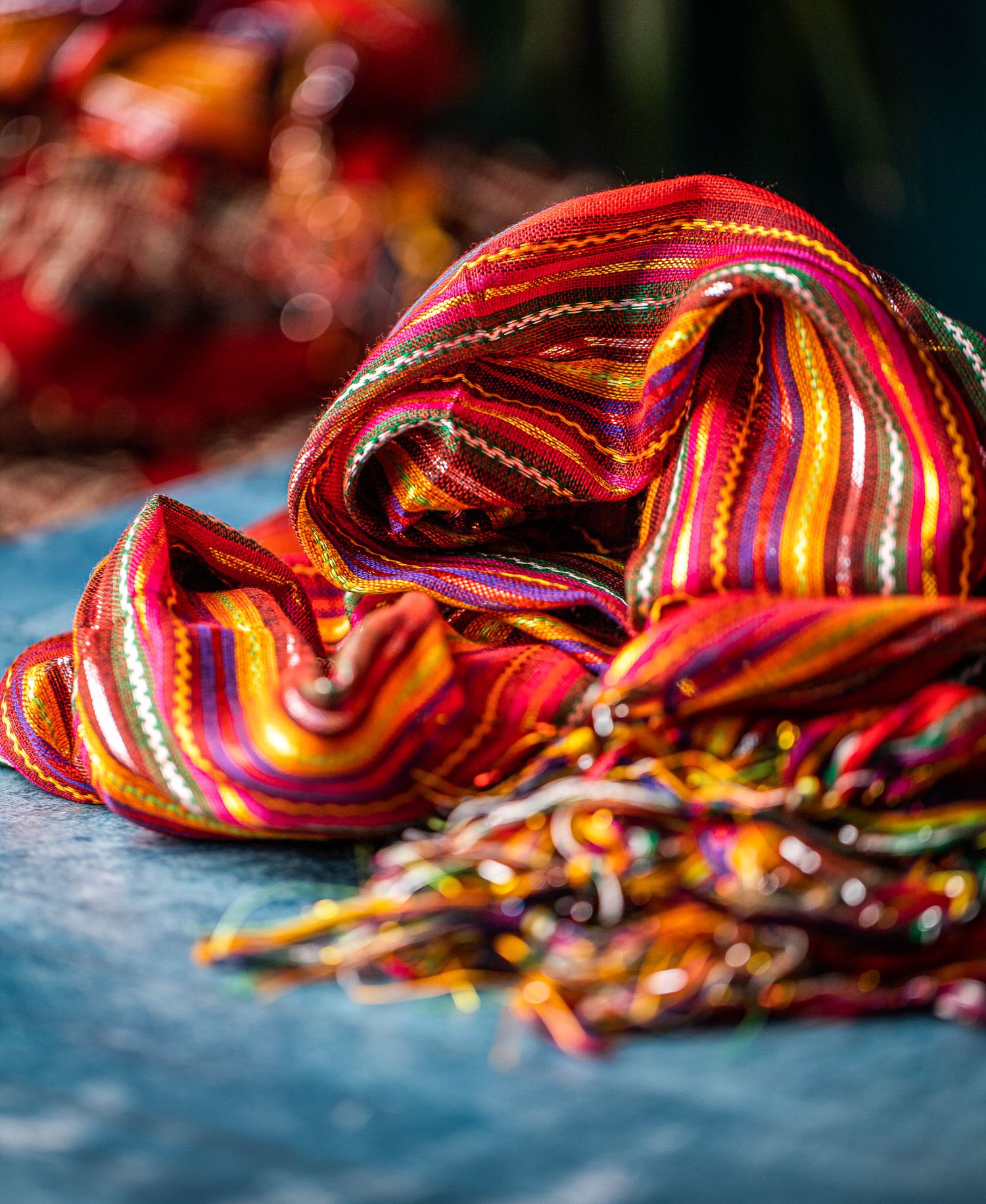 Colourful woven scarf with red, orange and yellow stripes on a textured surface, textile product photography Southampton