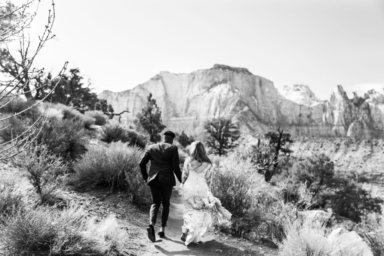 Black and white desert landscape with couple running through brush and mountains Zion National Park, UT.