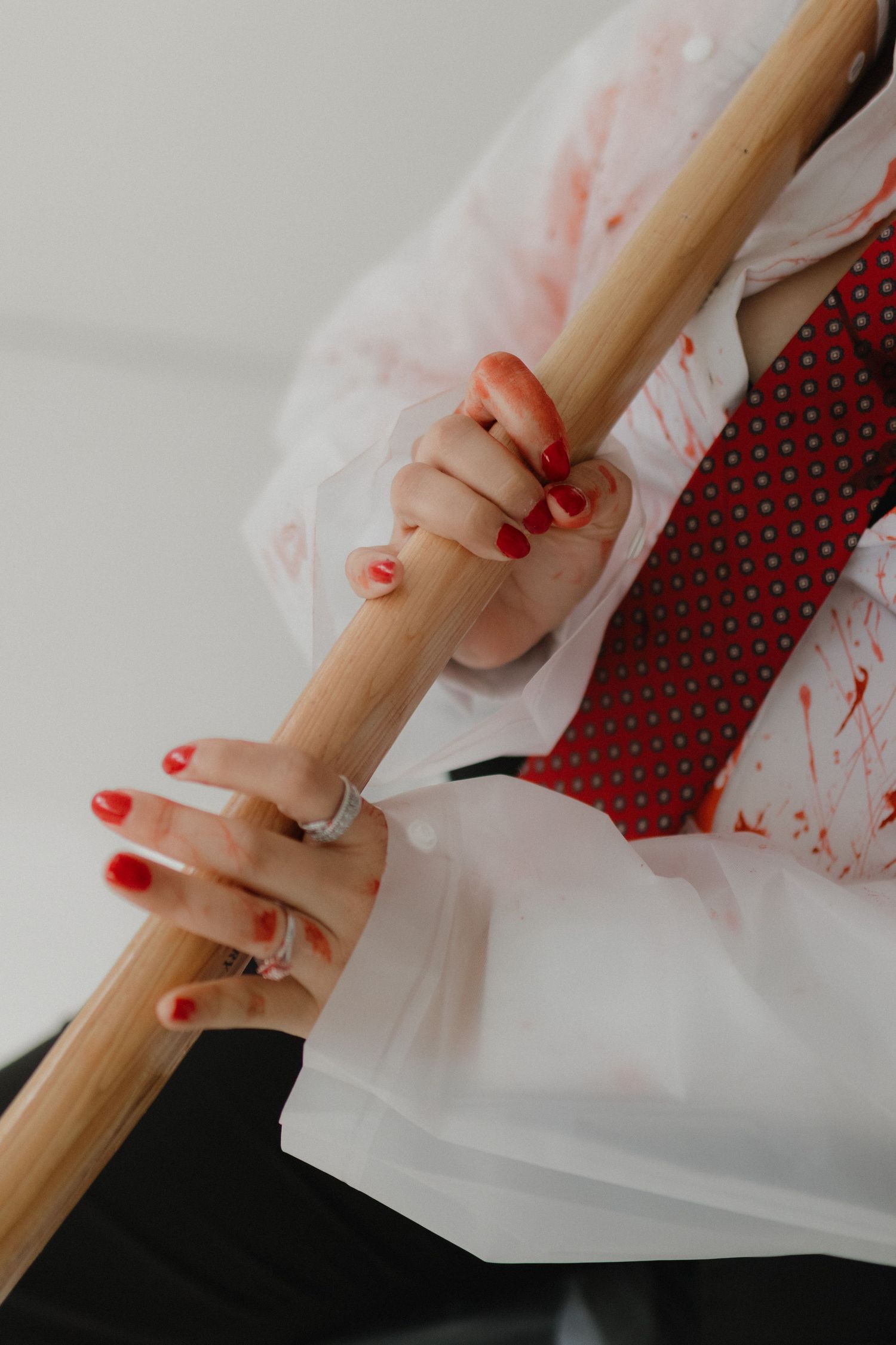 Close-up of hands with red nail polish gripping a wooden pole.