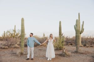 A couple poses among giant saguaro cacti during their desert photo session.